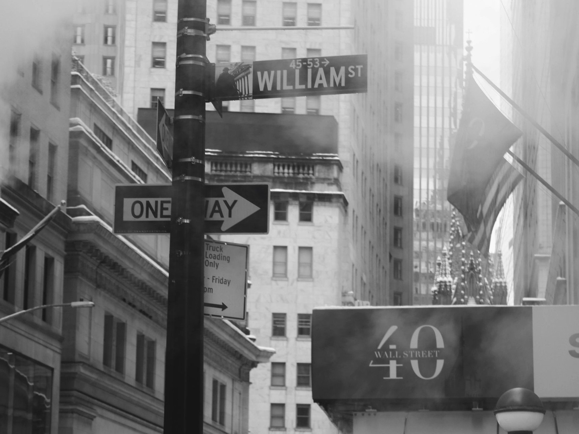 A black and white Manhattan street with a One Way sign