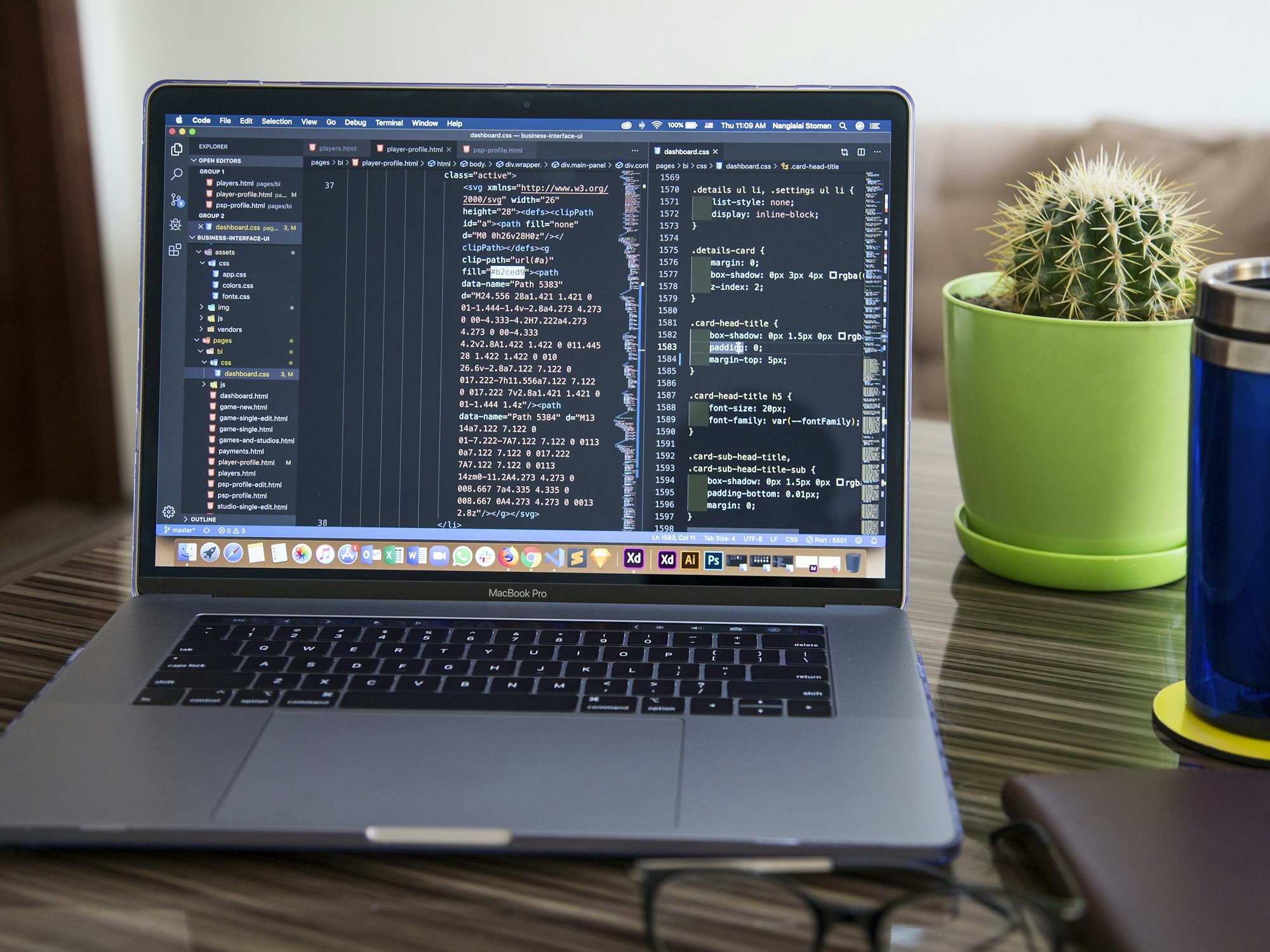 A laptop on a desk with a cactus and a coffee tumbler