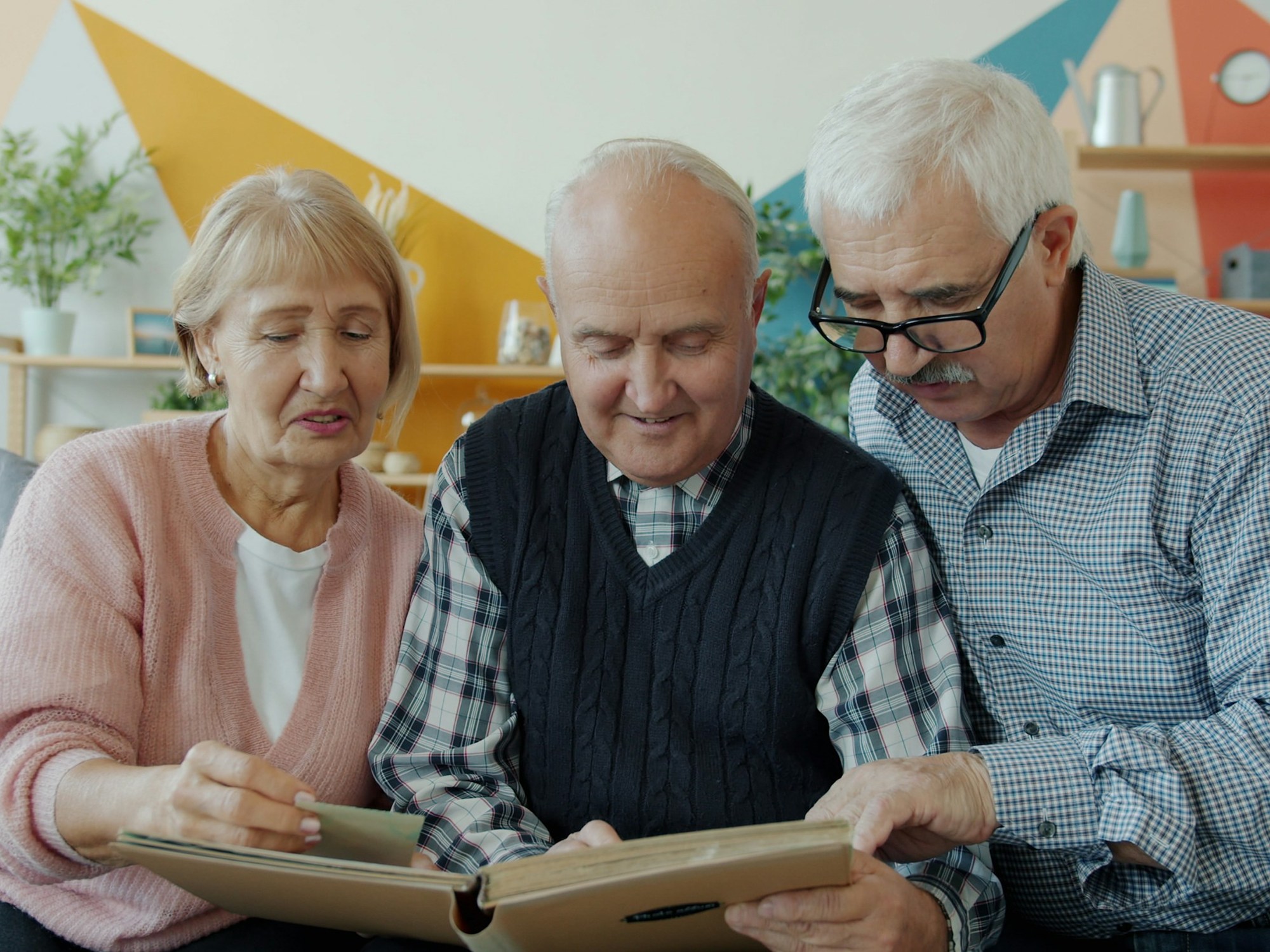 Three grandparents smiling over an open photo album