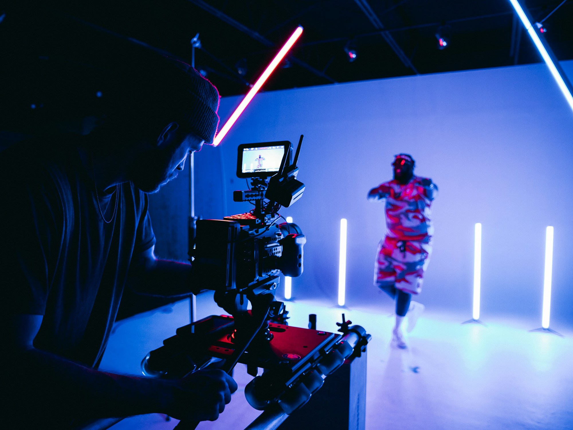 A camera operator filming a dancer on a neon-lit set