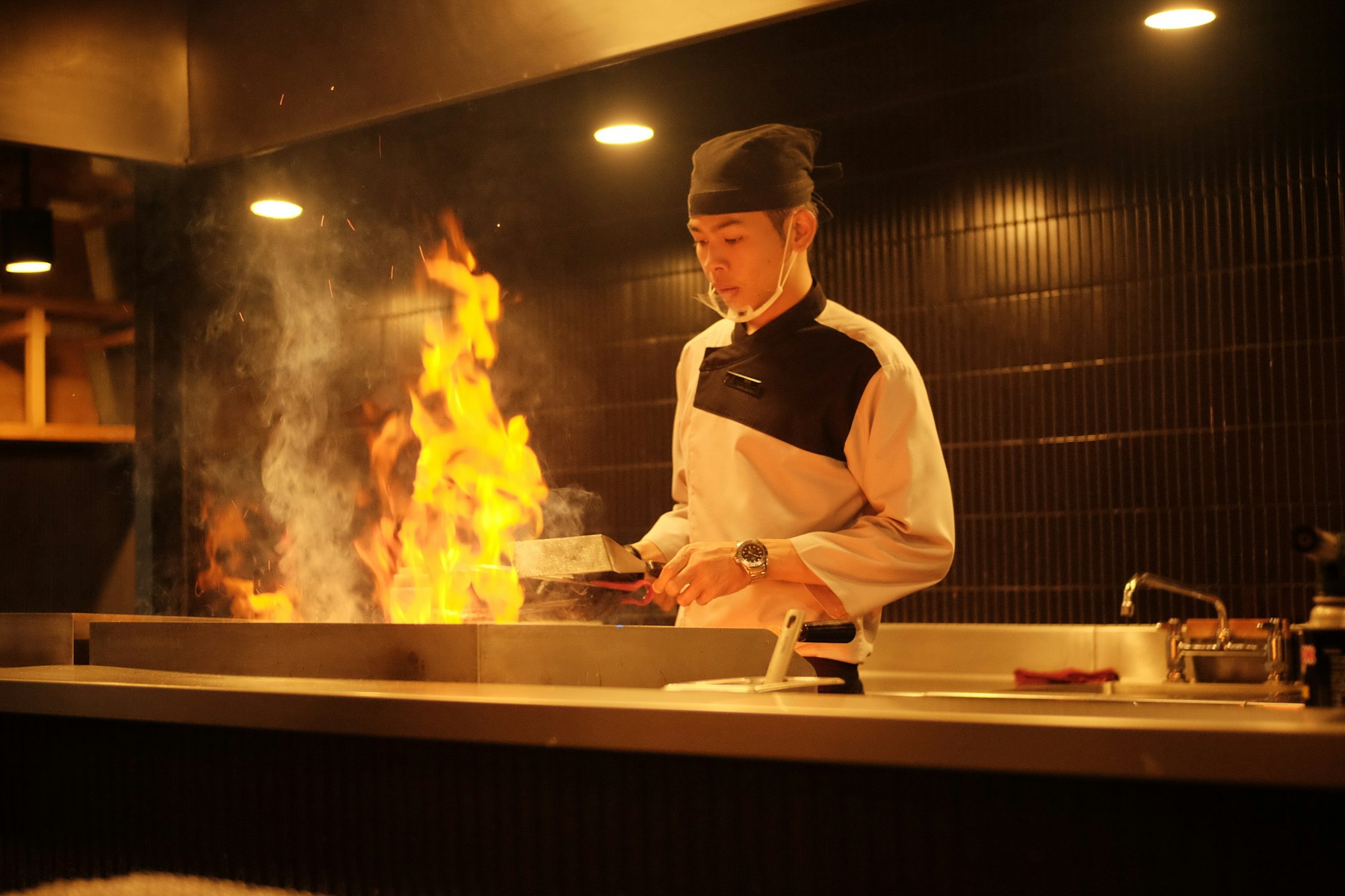 A chef cooking over flames in a restaurant kitchen