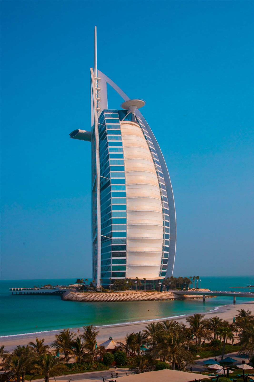 The Burj Al Arab hotel lit up at night, in a tall phone format